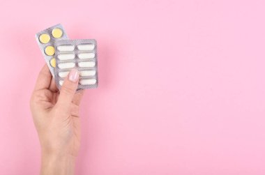 Pembe arka planda hapları olan el. Düz, yukarıdan görüntü. Uzayı kopyala, şablon.
