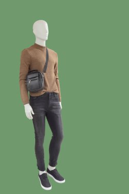 Yeşil arka planda izole edilmiş günlük kıyafetler giymiş uzun boylu erkek manken. Marka isimleri veya telif hakkı nesneleri yok.