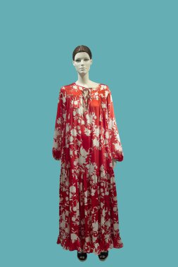 Modaya uygun giyinmiş, mavi arka planda izole edilmiş tam boy kadın mankeni. Marka isimleri veya telif hakkı nesneleri yok.