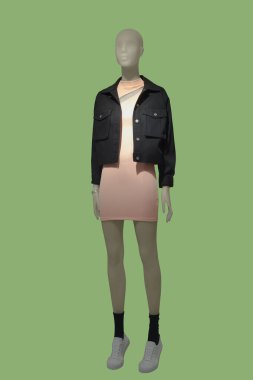 Modaya uygun giyinmiş, yeşil arka planda izole edilmiş tam boy kadın mankeni. Marka isimleri veya telif hakkı nesneleri yok.