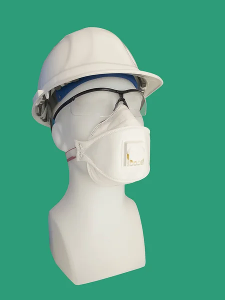 Dust mask with valve and safety helmet on a mannequin, isolated on green background.