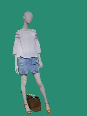 Modaya uygun giyinmiş, yeşil arka planda izole edilmiş tam boy kadın mankeni. Marka isimleri veya telif hakkı nesneleri yok.