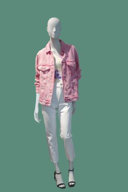 Uzun boylu, pembe kot ceket giymiş, yeşil arka planda izole edilmiş bir kadın mankeni. Marka isimleri veya telif hakkı nesneleri yok.