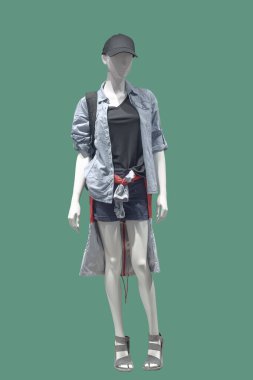 Modaya uygun giyinmiş, yeşil arka planda izole edilmiş tam boy kadın mankeni. Marka isimleri veya telif hakkı nesneleri yok.