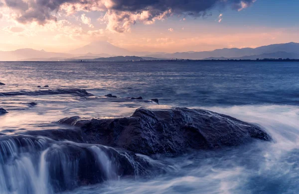 Kayalık deniz kıyısı, deniz ve günbatımında dalgalar. 