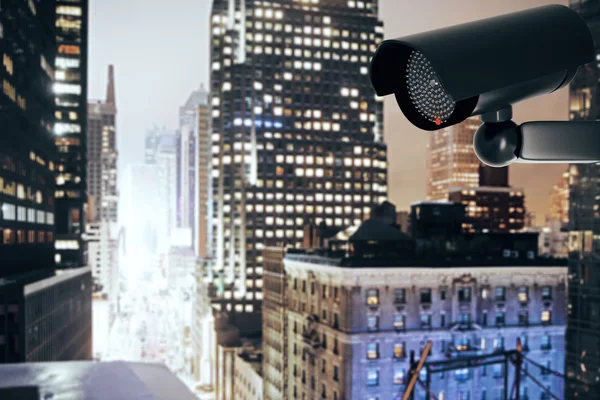 Black security camera on city background