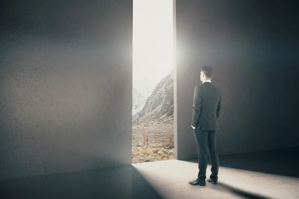 Homme d'affaires regardant par l'ouverture abstraite dans le mur avec la lumière du jour et la vue sur le paysage intérieur en béton. Concept de recherche. Rendu 3D — Photo