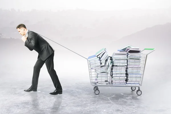 Mann schleppt Einkaufswagen mit Büchern — Stockfoto