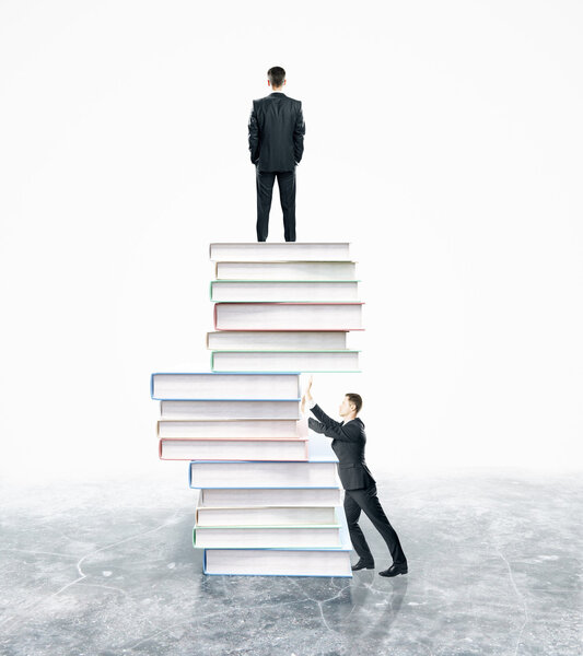 Businesspeople standing on and pushing abstract pile of books on white background. Competition concept