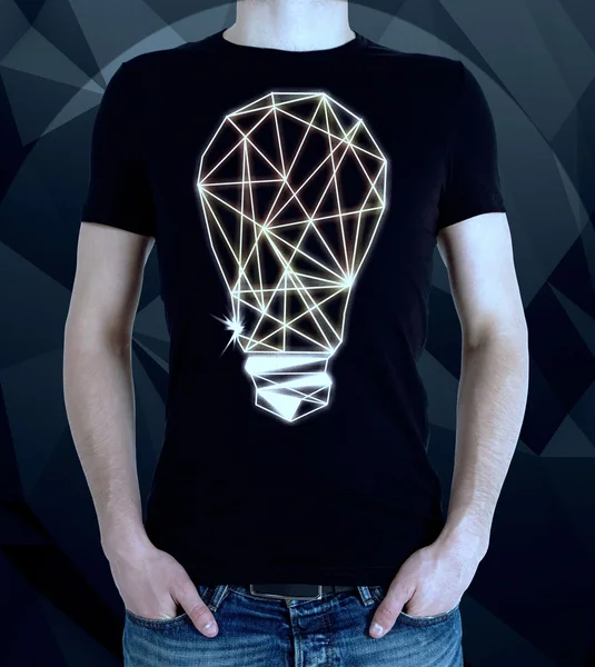 Young man wearing t-shirt with creative polygonal light bulb on dark background. Idea concept — Stock Photo, Image