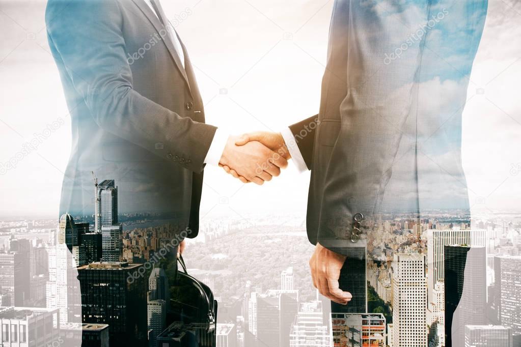 Businessmen shaking hands on city background. Double exposure. Partnership concept