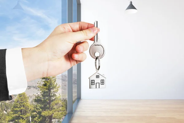 Hand holding key with house keychain in modern interior. Mortgage concept. 3D Rendering