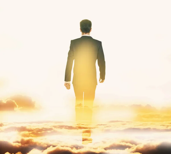 Achteraanzicht van de zakenman lopen op bewolkte hemelachtergrond. Succes concept — Stockfoto