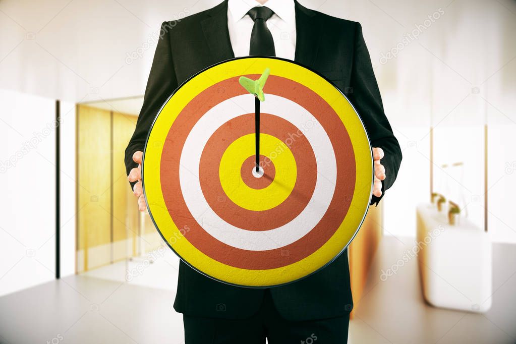 Businessman holding dartboard with arrow in the middle. Modern interior background. Aiming concept. 3D Rendering