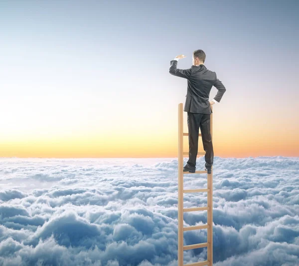 Бизнесмен на лестнице смотрит вдаль на фоне неба. Концепция исследования — стоковое фото