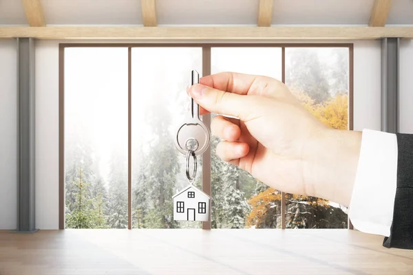 Close up of hand with key in modern interior with panoramic landscape view. Mortgage concept — Stock Photo, Image