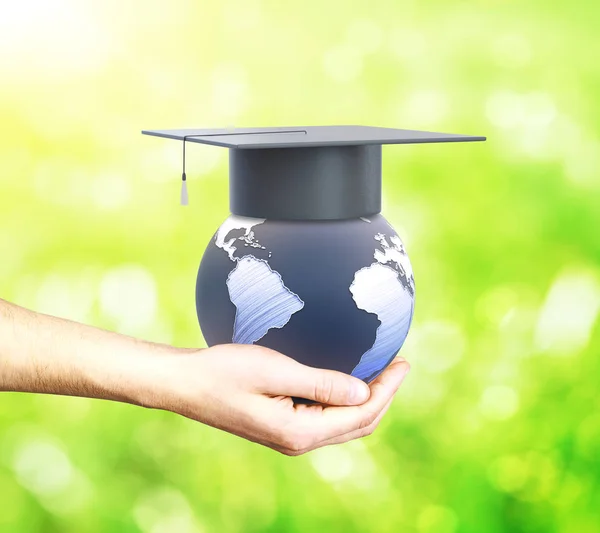 Hand som håller världen med examen cap på grön bakgrund. Utbildning utomlands koncept. 3D-rendering. Delar av denna bild från Nasa — Stockfoto