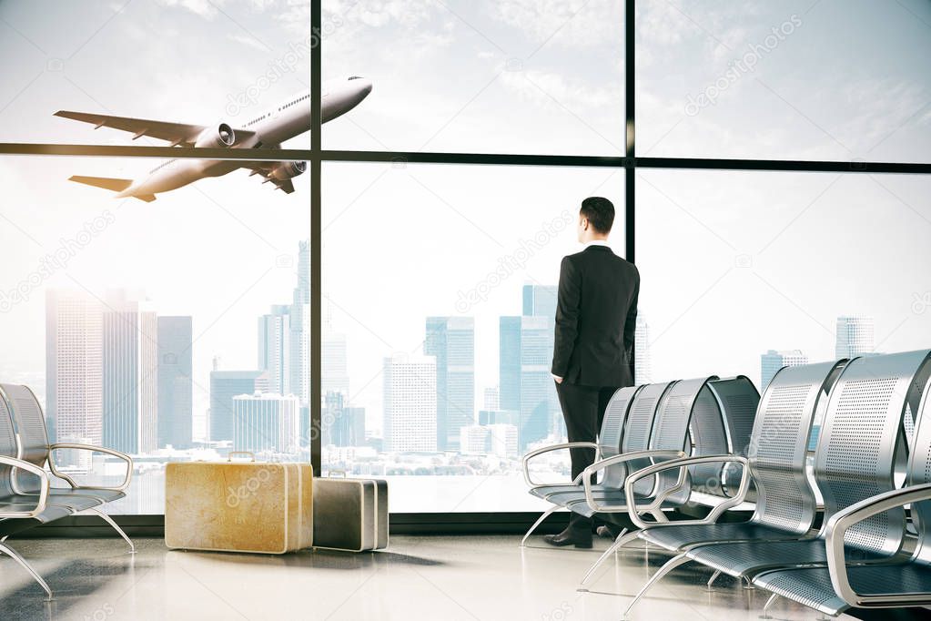 Businessman looking out of window in airport interior with steel seats, luggage and panoramic sky view with flying by plane. 3D Rendering