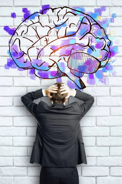 Vista posteriore di uomo d'affari stressato su sfondo mattone con schizzo cervello. Concetto di brainstorming — Foto Stock
