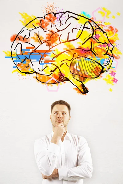 Portrait of thoughtful young businessman on concrete background with brain sketch. Brainstorm concept — Stock Photo, Image