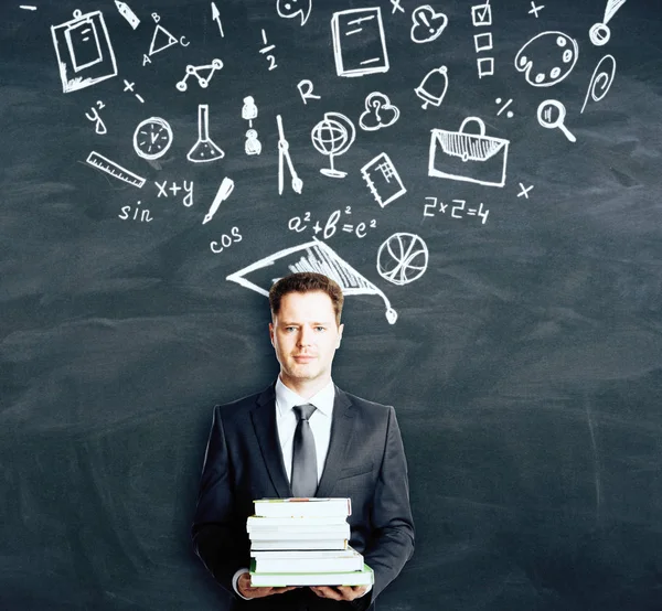 Zakenman houden van boeken over schoolbord achtergrond met onderwijs tekeningen. Science-concept — Stockfoto