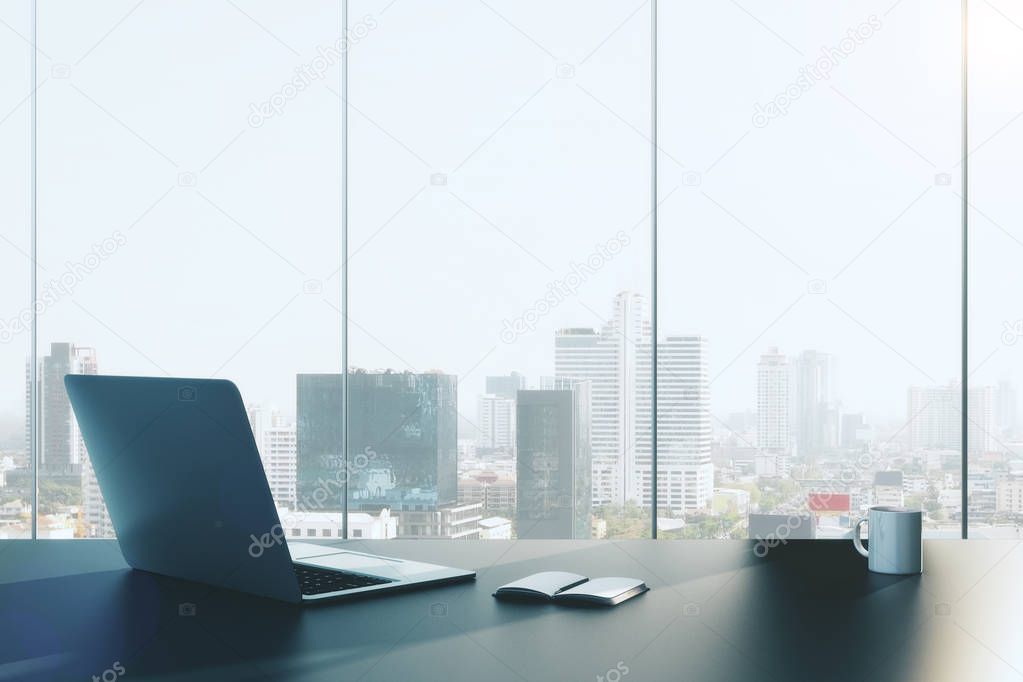 Front view of office workplace with open laptop, notepad and coffee cup on panoramic city view background. 3D Rendering