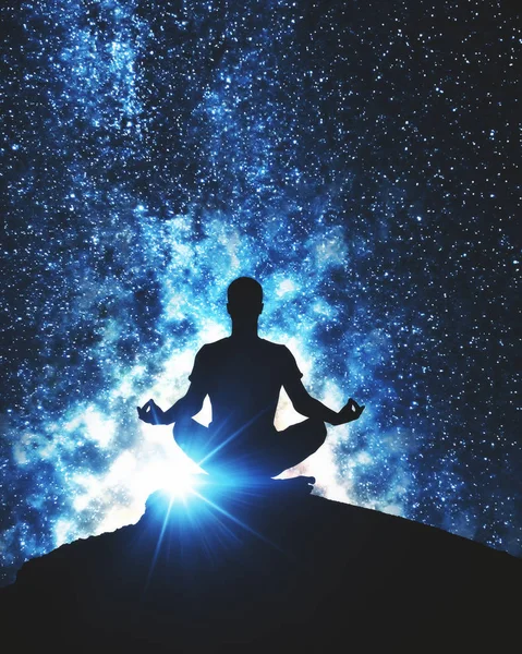 Back view of meditating man on mountain top. Space background. Yoga concept