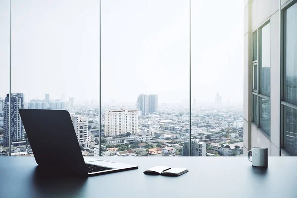 Office Masaüstü açık dizüstü bilgisayar, not defteri, kahve Kupası ve şehir görünümü ile. — Stok fotoğraf