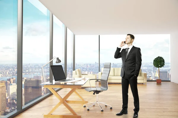 Junger Geschäftsmann telefoniert in einem modernen Bürointerieur mit Arbeitsplatz, Lounge-Bereich und Blick auf die Stadt. Kommunikationskonzept. 3D-Darstellung — Stockfoto