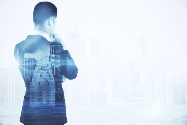Back view of thoughtful young businessman on abstract city background with copy space. Double exposure. Employment concept — Stock Photo, Image