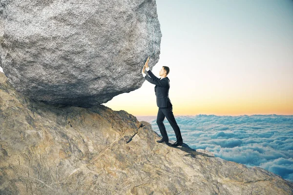 Side view of young businessman pushing huge rock up mountain. Beautiful background. Perseverance concept — Stock Photo, Image