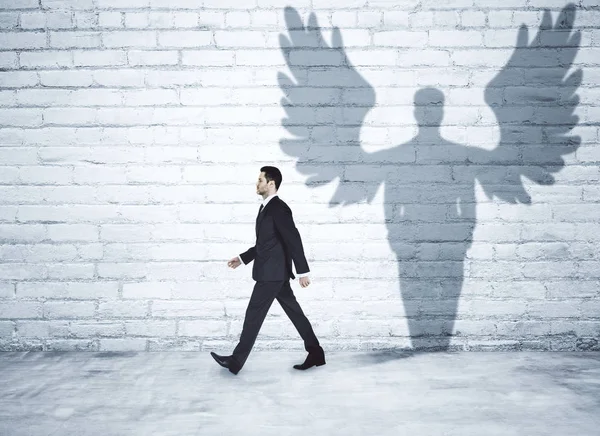 Walking businessman with angel shadow Stock Image