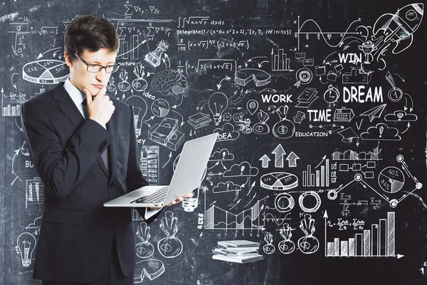 Όμορφος νεαρός επιχειρηματίας χρησιμοποιώντας φορητό υπολογιστή ob Μαυροπίνακας φόντο με επαγγελματίες σκίτσο. Έννοια επικοινωνίας — Φωτογραφία Αρχείου