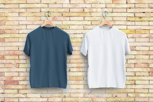 Kleiderbügel mit leeren grauen und weißen T-Shirts hängen an der Wand. Bekleidungskonzept — Stockfoto