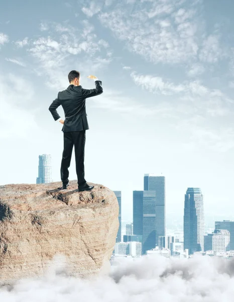 Şehir arka plan üzerinde mesafe bakarak bir kayanın üzerinde duran ve iş adamı. Gelecekteki kavramı — Stok fotoğraf