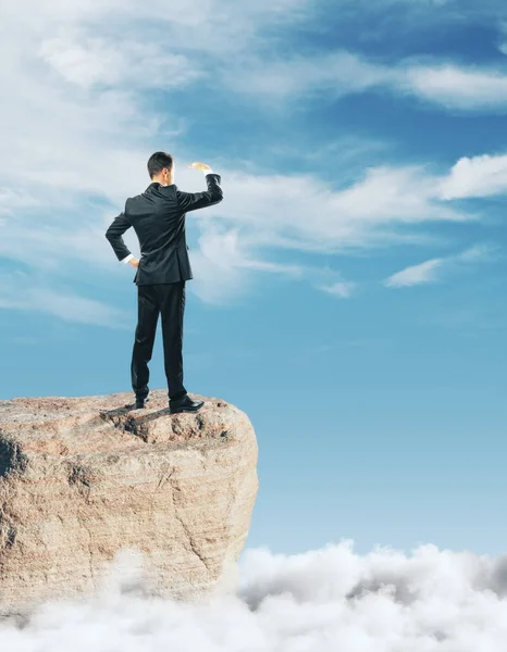 Affärsman står på rock och tittar in i distansera på himmel bakgrund. I morgon koncept — Stockfoto
