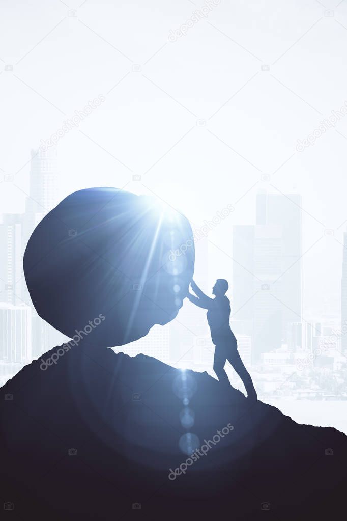 Backlit image of businessman pushing boulder uphill. Bright background with sunlight. Challenge concept.