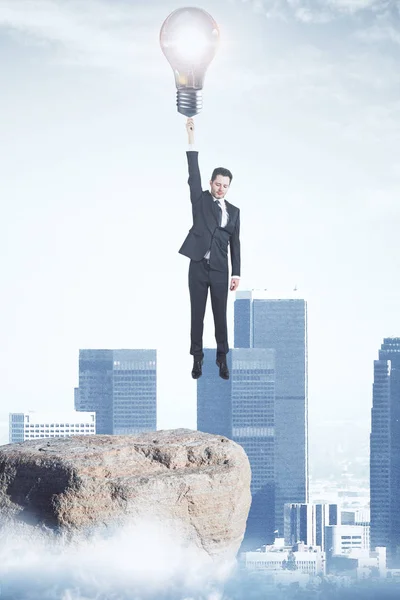 Flying businessman with lamp on light city background. Genius concept — Stock Photo, Image