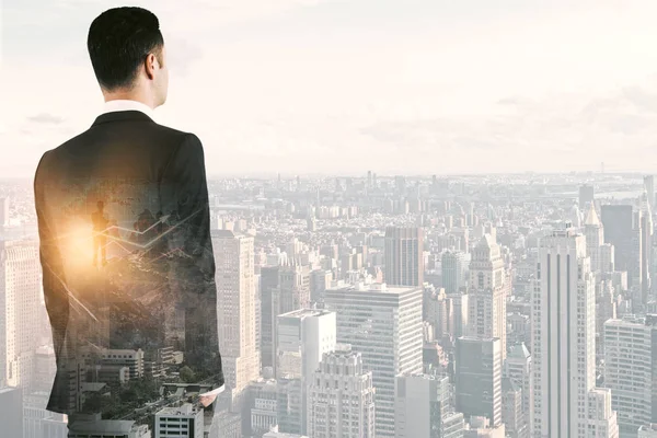 Back view of thoughtful young businessman with forex chart on bright city background with copy space and sunlight. Finance concept. Double exposure — Stock Photo, Image