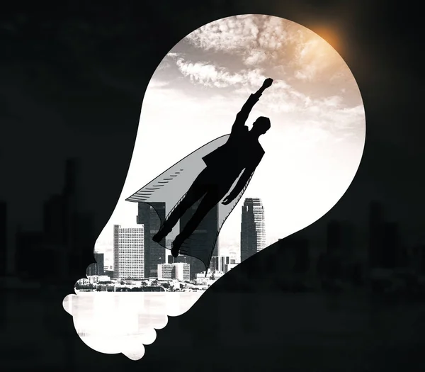 Abstract image of flying man hero with cape and light bulb silhouette on black city background. Courage concept