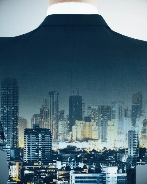 Back view of thoughtful businessman silhouette on city background. Think concept. Double exposure