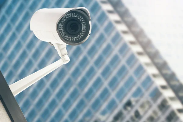 Primer plano de la cámara CCTV con el edificio de vidrio moderno borroso en el fondo. Concepto de vídeo. Renderizado 3D — Foto de Stock