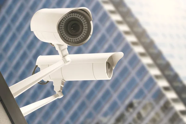 Gros plan des caméras de vidéosurveillance avec un bâtiment en verre moderne flou en arrière-plan. Concept d'alerte. Rendu 3D — Photo