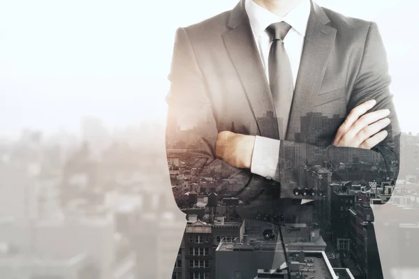 Hombre de negocios irreconocible con los brazos cruzados de pie en el fondo abstracto de la ciudad. Mañana concepto. Doble exposición —  Fotos de Stock