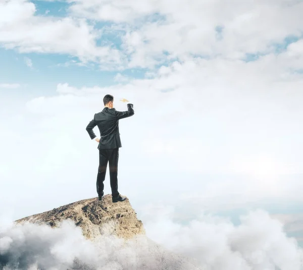 Uomo d'affari in piedi sulla cima della montagna e guardando in lontananza . — Foto Stock