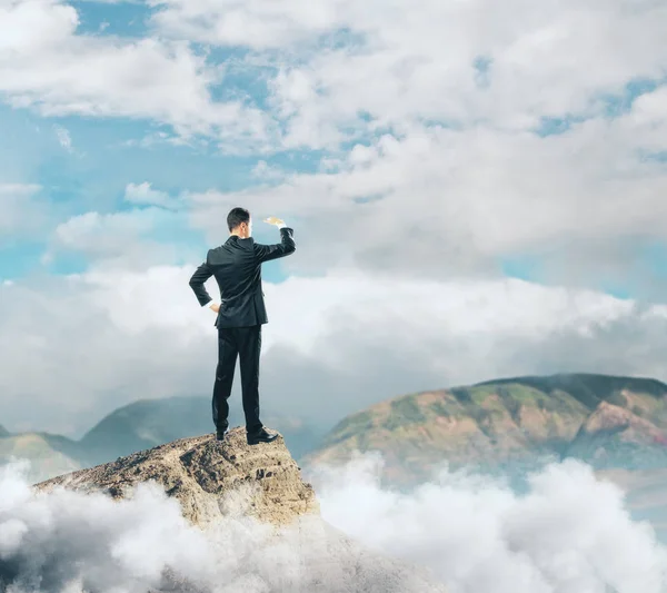 Mladý podnikatel, stojící na vrcholu hory a při pohledu do dálky — Stock fotografie