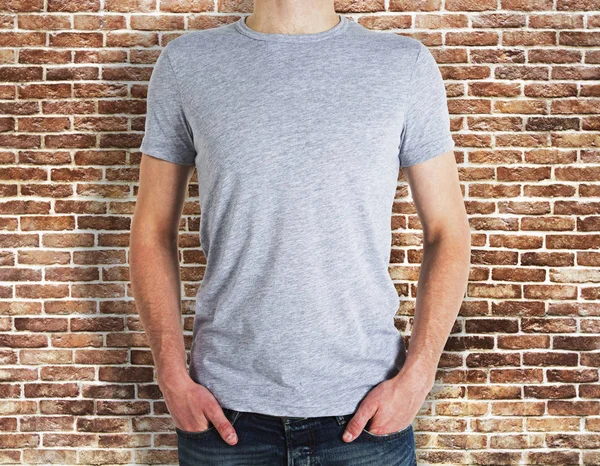Man wearing grey t-shirt on brick background — Stock Photo, Image