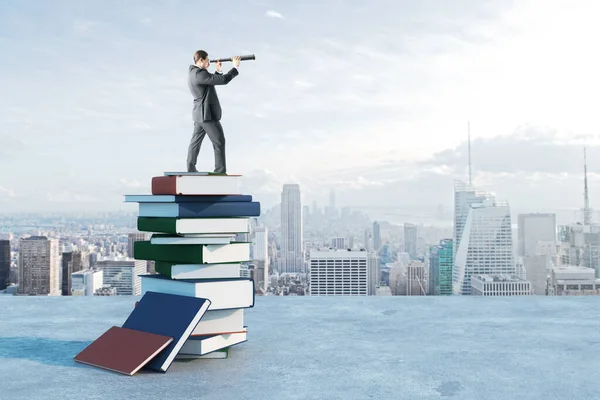 Businessman with binoculars standing on book