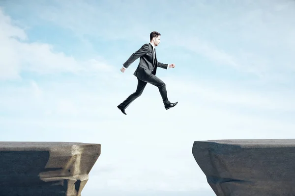 Businessman in suit jumping on mountain