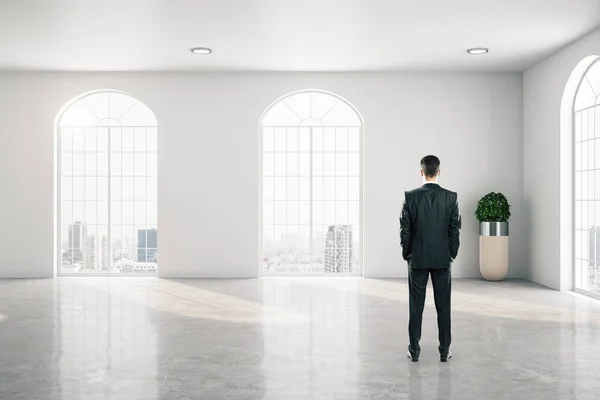 Бизнесмен, стоящий в интерьере галереи с большим окном — стоковое фото